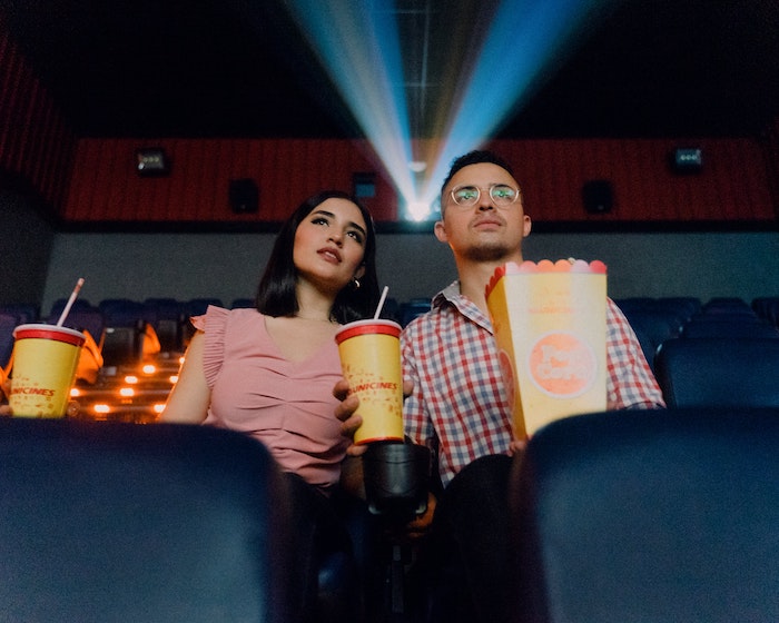 un couple de jeunes étudiants au cinéma qui mange des popcorns