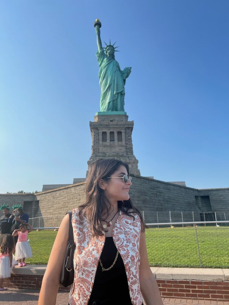 Une étudiante devant la statue de la liberté à New York